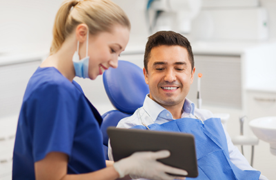 female dentist with tablet pc and male patient female hygienist and male patient at Centre for Holistic and Biological Dentistry